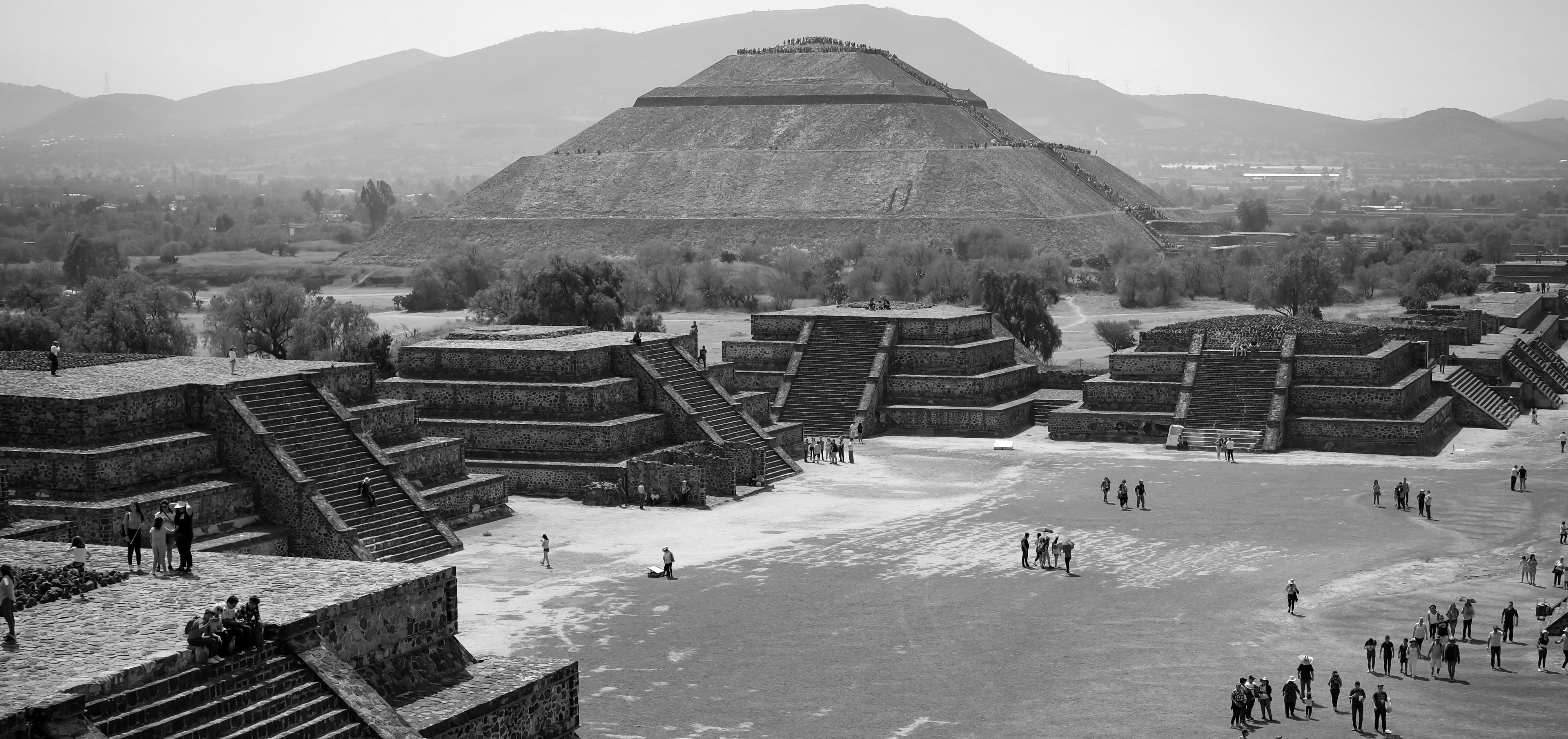 Black and white image of the Pyramid of the Sun at Teotihuacan with people around.